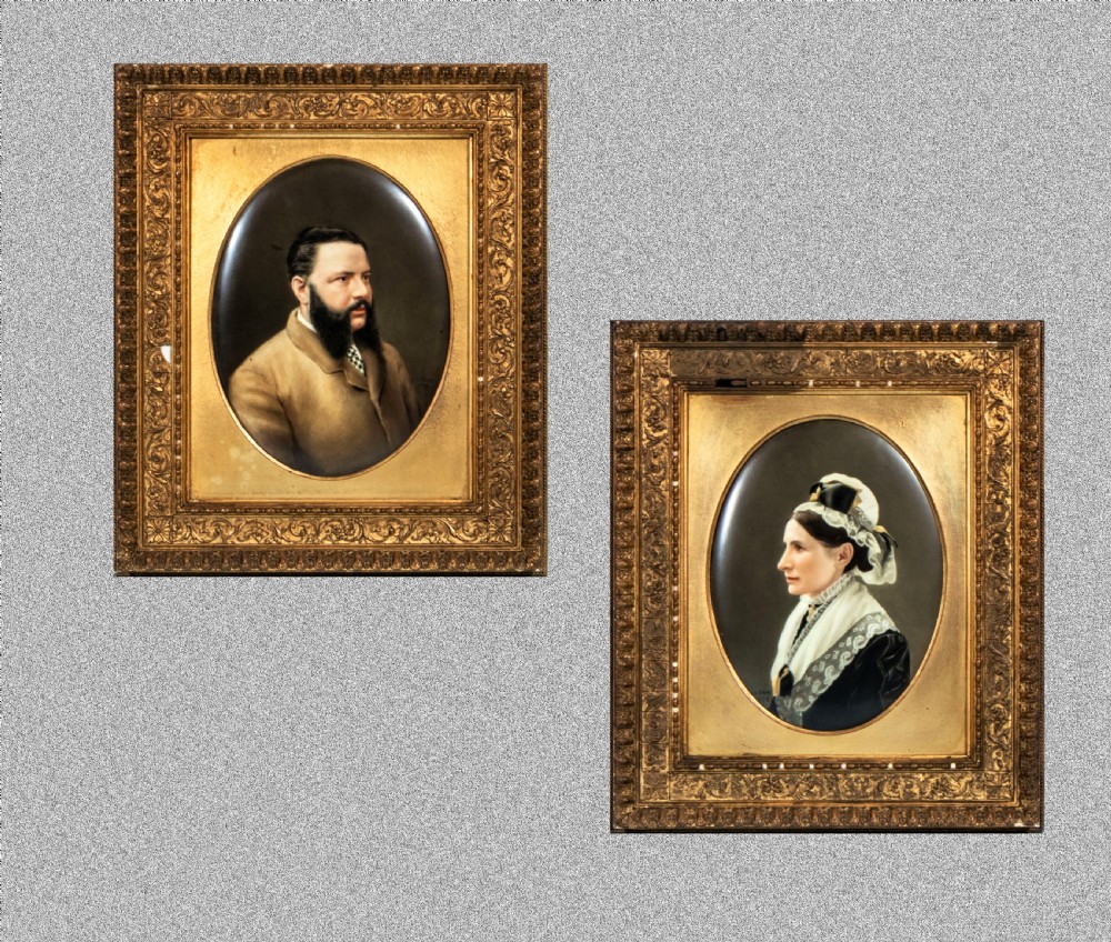 A pair of 19th-century rectangular giltwood frames displaying oval porcelain plaques hand-painted with realistic portraits of a gentleman and a lady.