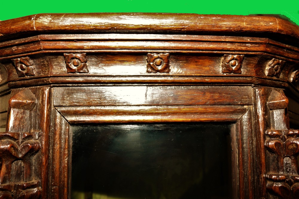 A dark carved oak Gothic Revival display cabinet featuring a glazed upper section, patterned fabric lining, and detailed linenfold panelling on the lower frame. View XII