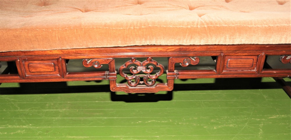 A carved dark hardwood Chinese daybed featuring a stepped backrest with marble panel inserts and a tufted light brown cushioned seat. View II