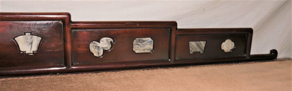 A carved dark hardwood Chinese daybed featuring a stepped backrest with marble panel inserts and a tufted light brown cushioned seat. View III