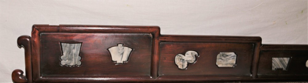 A carved dark hardwood Chinese daybed featuring a stepped backrest with marble panel inserts and a tufted light brown cushioned seat. View IV