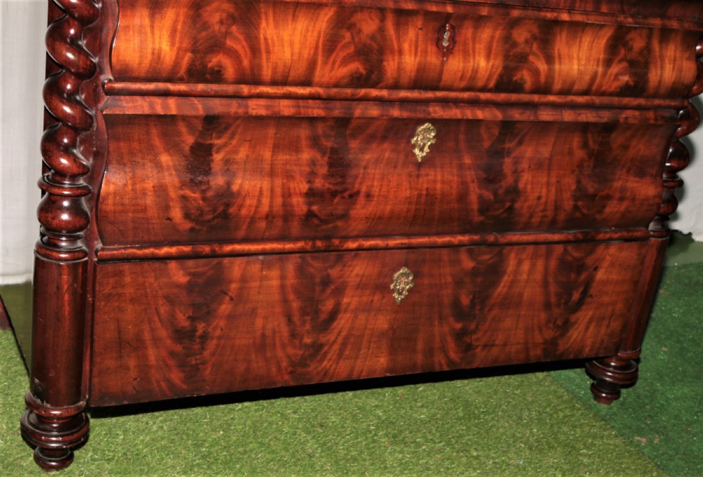 A Biedermeier flame mahogany fall-front bureau desk featuring twisted side columns, multiple drawers, brass keyhole escutcheons, and urn finials. View II