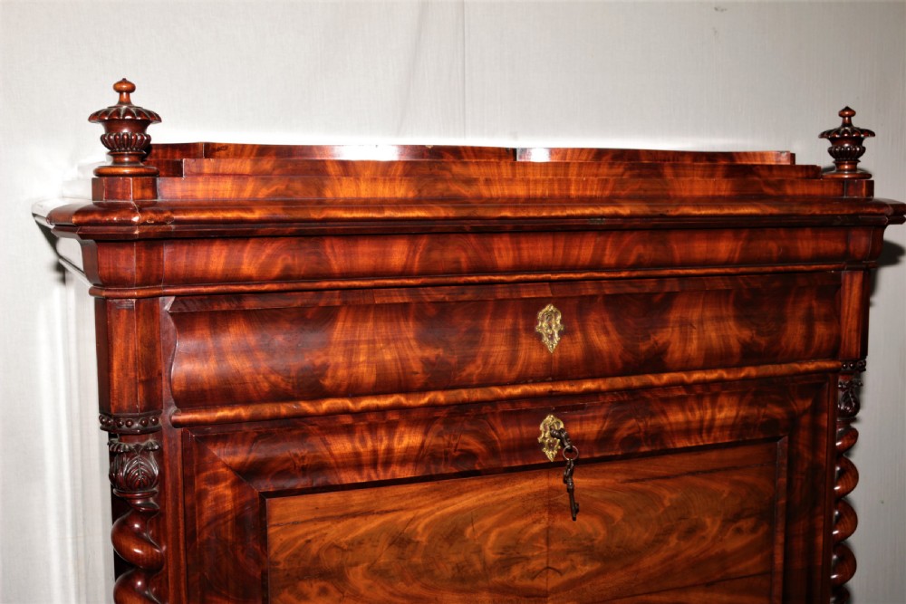 A Biedermeier flame mahogany fall-front bureau desk featuring twisted side columns, multiple drawers, brass keyhole escutcheons, and urn finials. View III