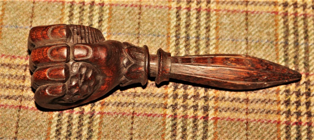 A Victorian hand-carved dark wood nutcracker designed in the shape of a clenched fist with a threaded screw handle.