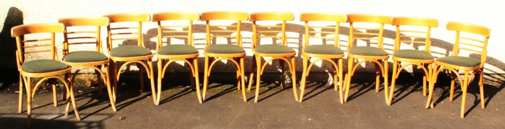 A set of ten light wood bentwood dining chairs with curved backs and green patterned fabric seat pads. View II