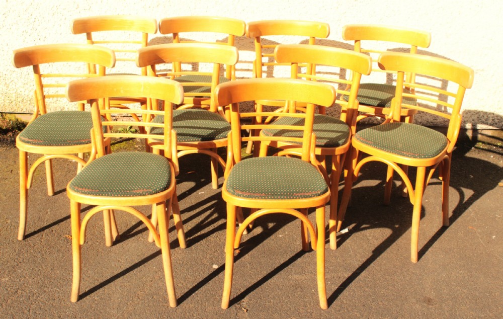 A set of ten light wood bentwood dining chairs with curved backs and green patterned fabric seat pads. View V