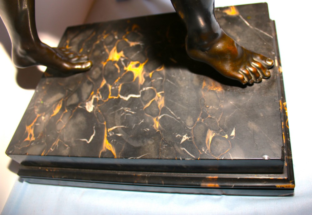 A dark patinated bronze sculpture of a dancing faun with raised arms mounted on a square marble base. View VII