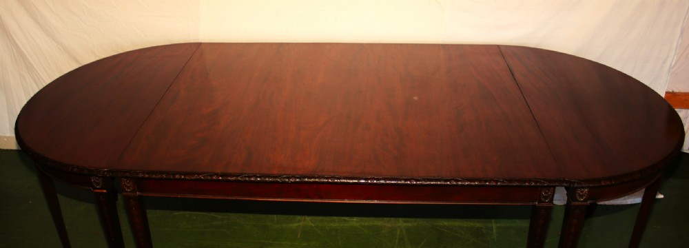 An antique dark mahogany extending dining table featuring removable leaves, D-shaped end sections, and tapered square legs with carved detailing. View II