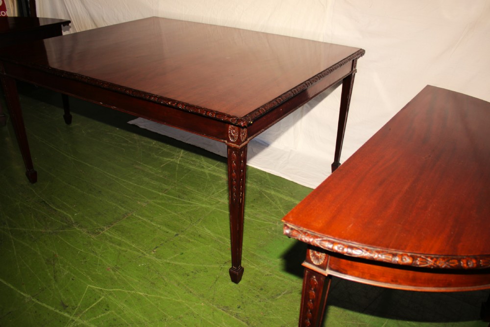 An antique dark mahogany extending dining table featuring removable leaves, D-shaped end sections, and tapered square legs with carved detailing. View III