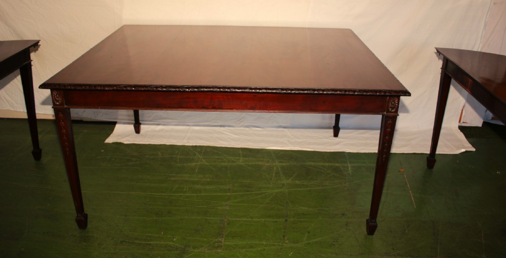 An antique dark mahogany extending dining table featuring removable leaves, D-shaped end sections, and tapered square legs with carved detailing. View VI