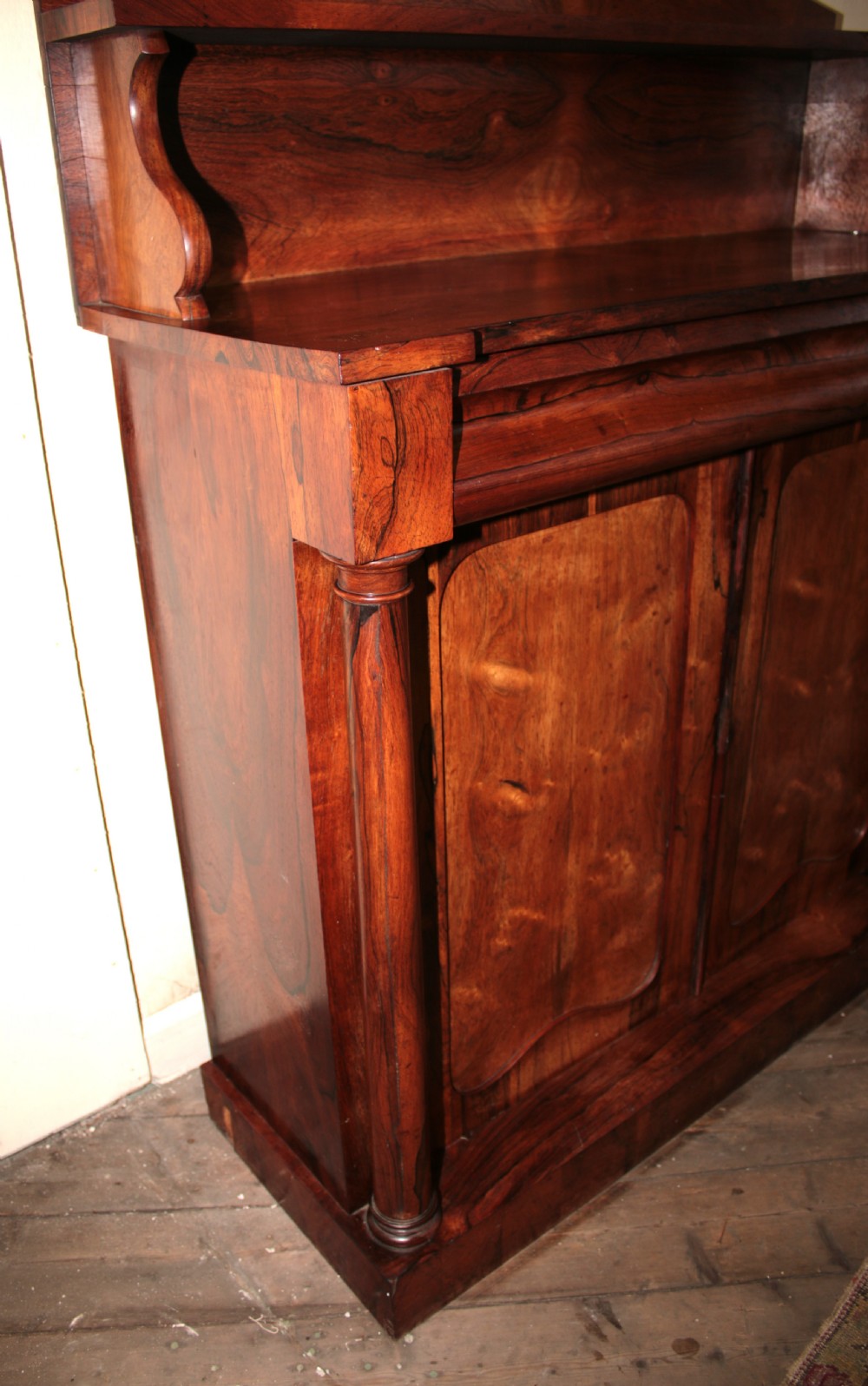 A Victorian rosewood chiffonier featuring a raised top display shelf, flame veneer cupboard doors, and turned side columns on a solid plinth base. View II