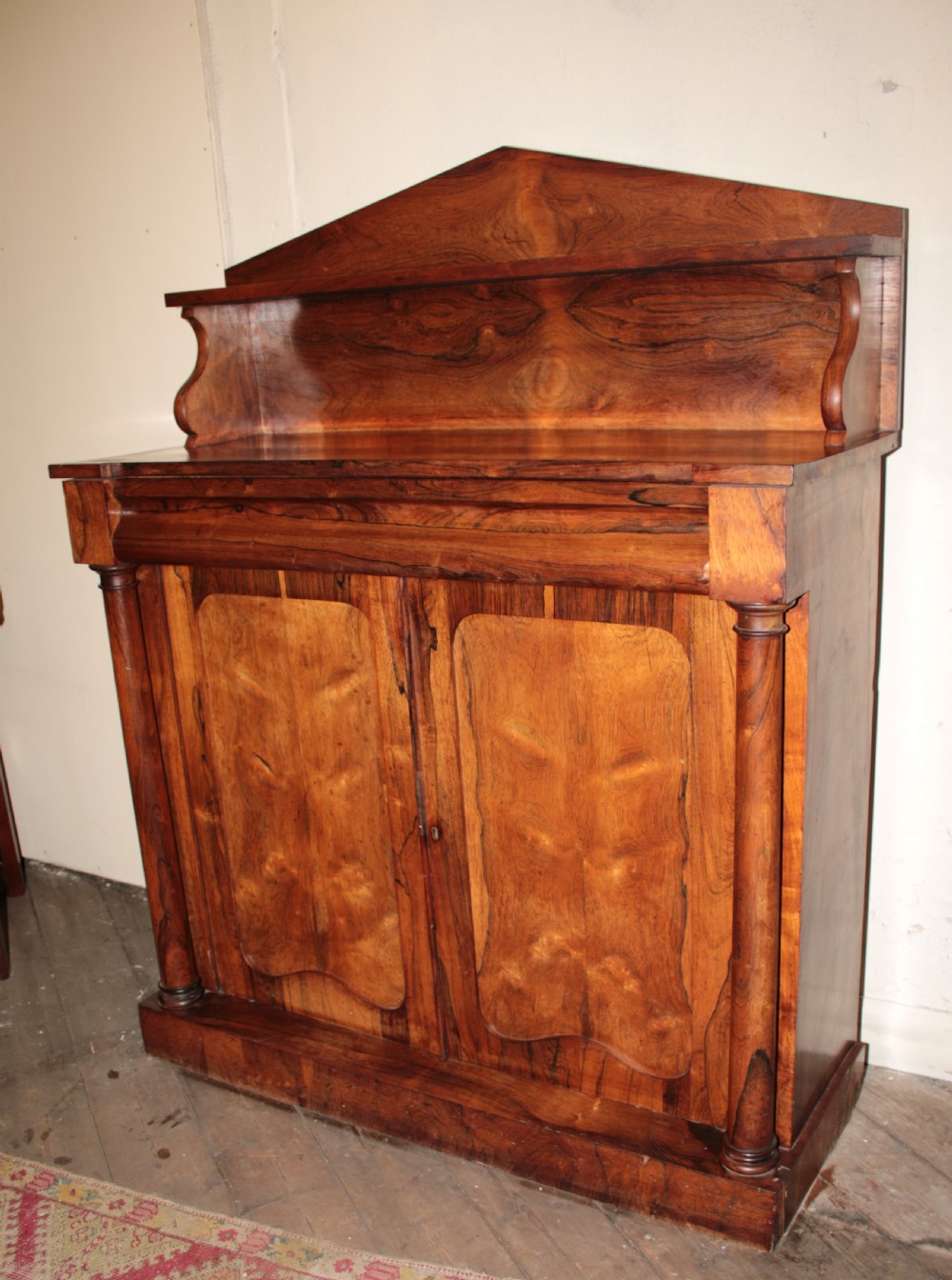 A Victorian rosewood chiffonier featuring a raised top display shelf, flame veneer cupboard doors, and turned side columns on a solid plinth base. View IV