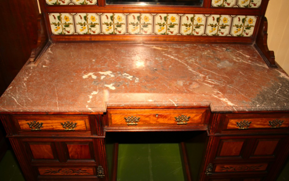 An Aesthetic Movement walnut washstand featuring a marble counter top, tiled splashback with central mirror, spindle gallery, and twin pedestal cupboards. View V