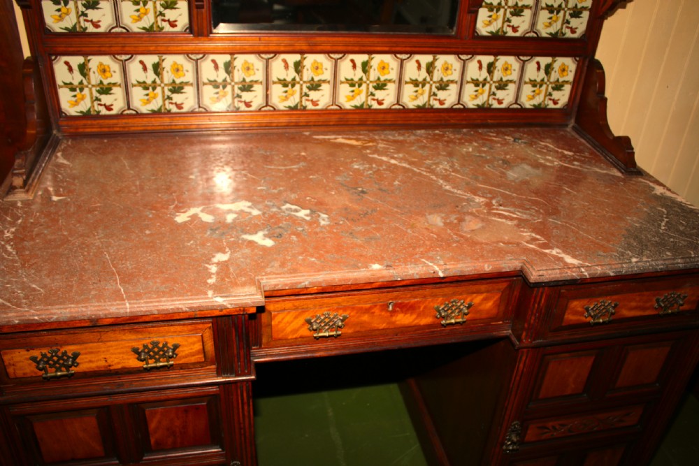 An Aesthetic Movement walnut washstand featuring a marble counter top, tiled splashback with central mirror, spindle gallery, and twin pedestal cupboards. View VI