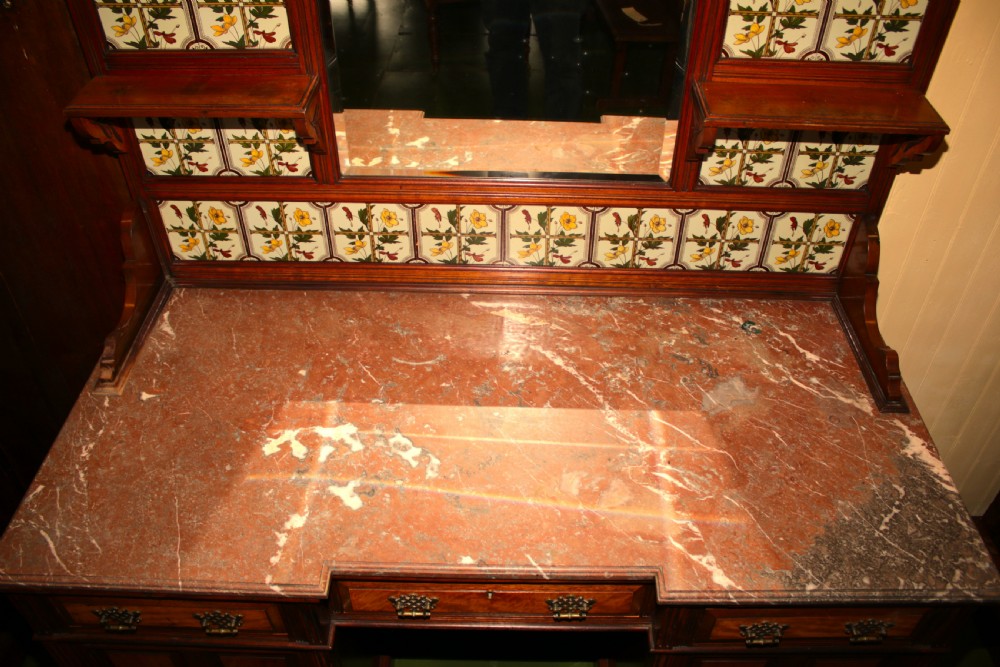 An Aesthetic Movement walnut washstand featuring a marble counter top, tiled splashback with central mirror, spindle gallery, and twin pedestal cupboards. View XIV