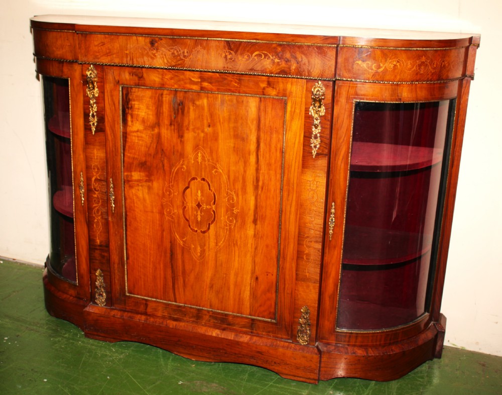 A Victorian walnut credenza featuring central marquetry inlay, curved glazed side display doors, and gilt bronze mounts.