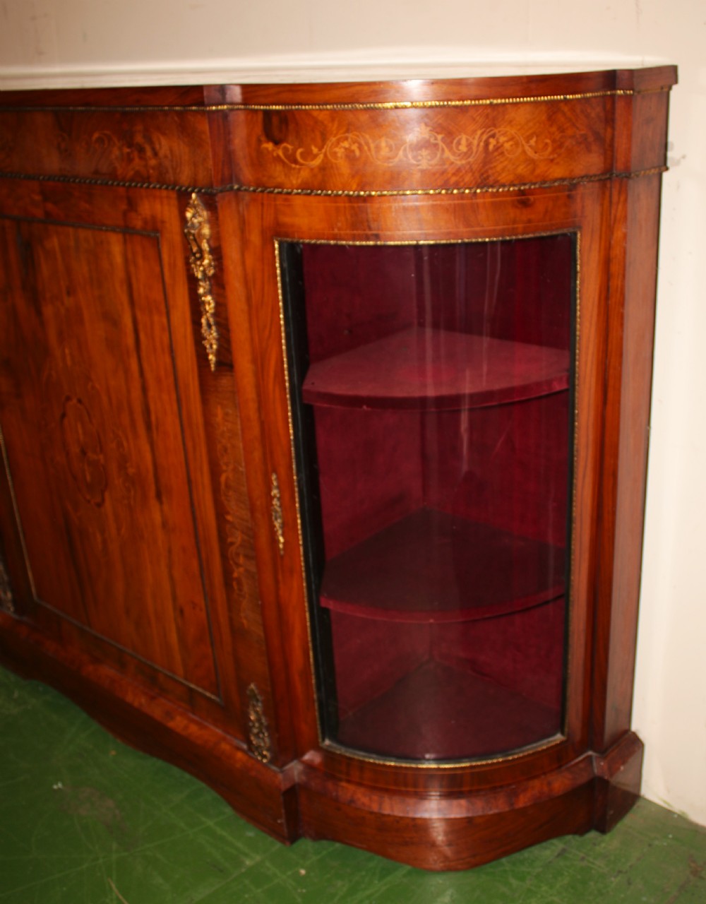 A Victorian walnut credenza featuring central marquetry inlay, curved glazed side display doors, and gilt bronze mounts. View II