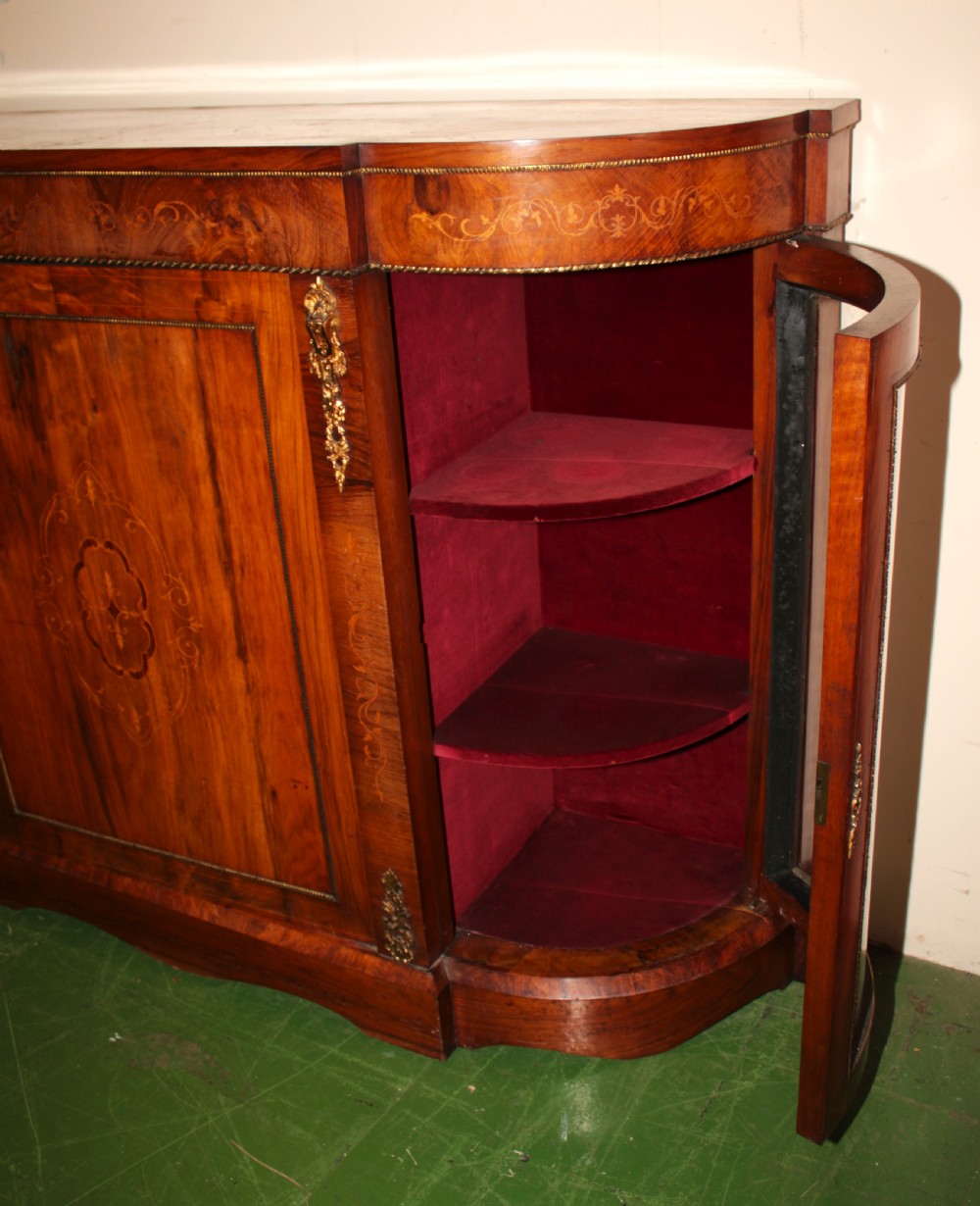 A Victorian walnut credenza featuring central marquetry inlay, curved glazed side display doors, and gilt bronze mounts. View IV