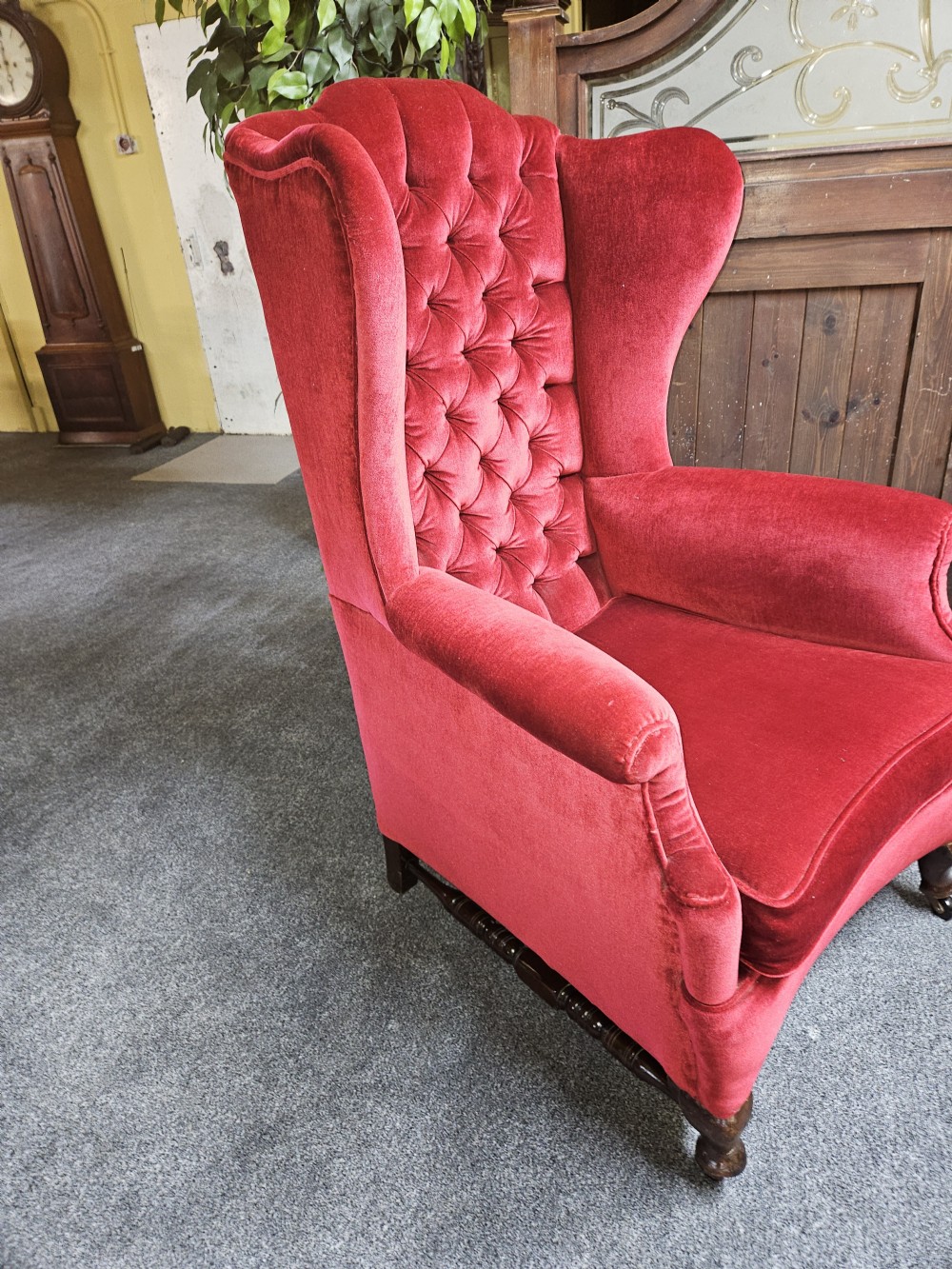 A Victorian high-back wing chair upholstered in red velvet with diamond button tufting and turned timber front legs on castors. View VII