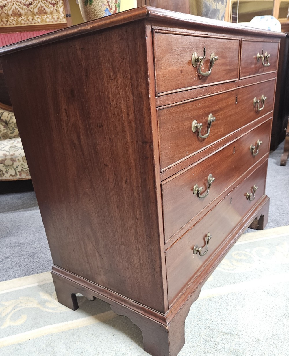 A rectangular Georgian mahogany chest of drawers featuring two short drawers over three long graduated drawers, fitted with brass swing handles and key escutcheons, raised on bracket feet. View III