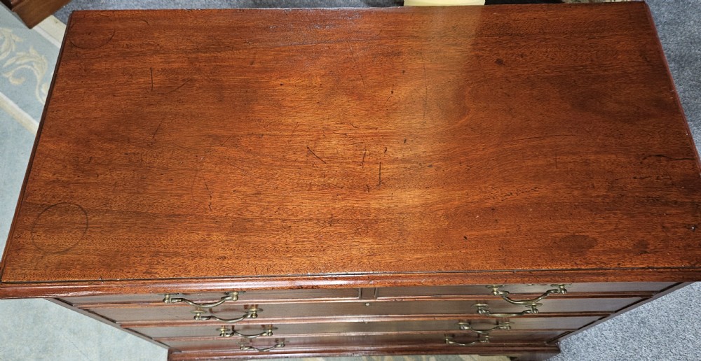 A rectangular Georgian mahogany chest of drawers featuring two short drawers over three long graduated drawers, fitted with brass swing handles and key escutcheons, raised on bracket feet. View IV