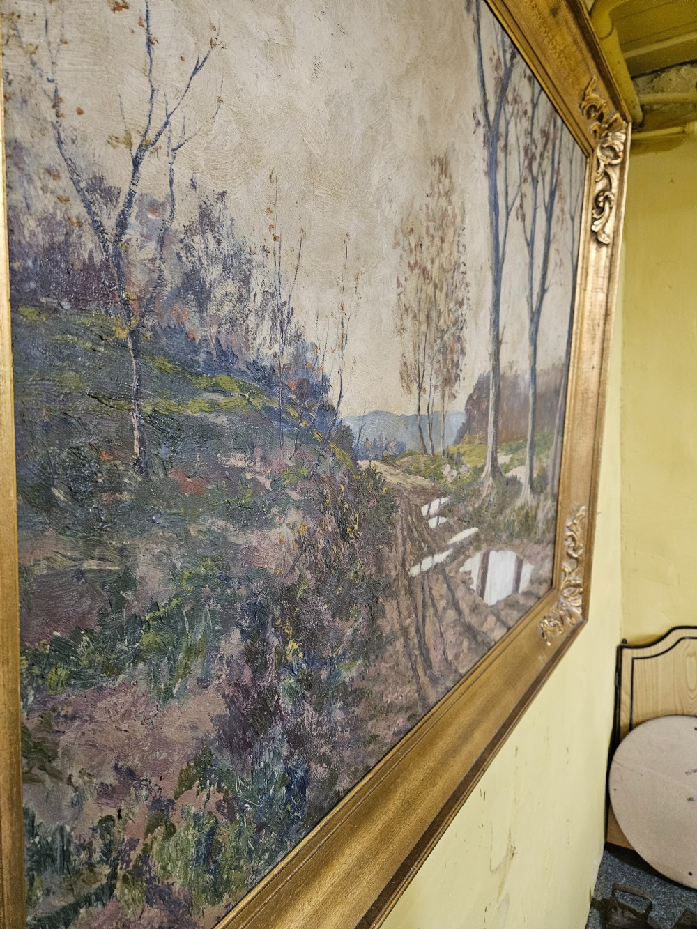 A large framed oil painting depicting a muddy countryside path lined with bare trees under an overcast sky, housed in an ornate gilt frame. View VIII