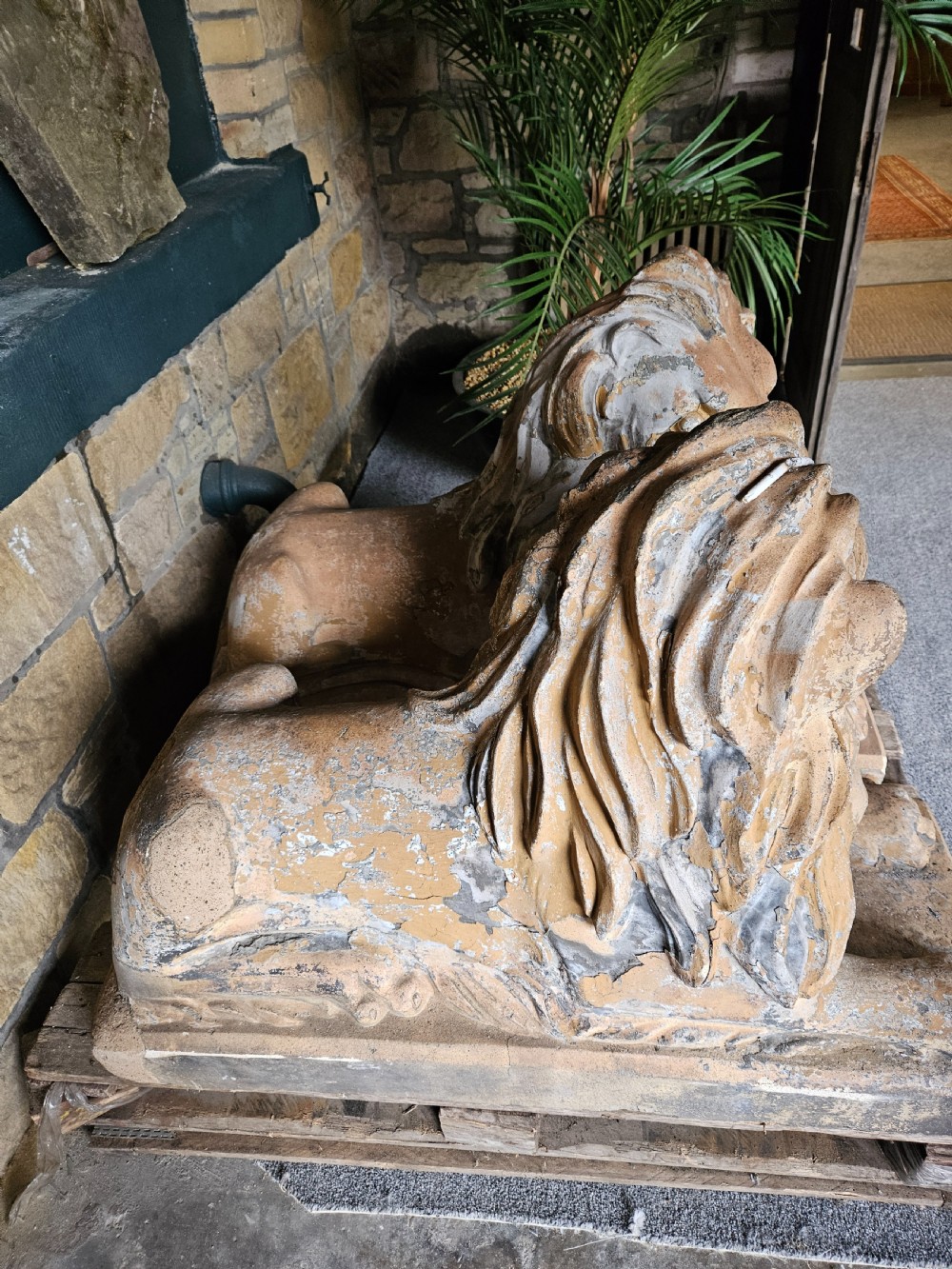 A pair of sculpted buff stone recumbent lion statues with detailed manes resting on integrated rectangular bases. View II