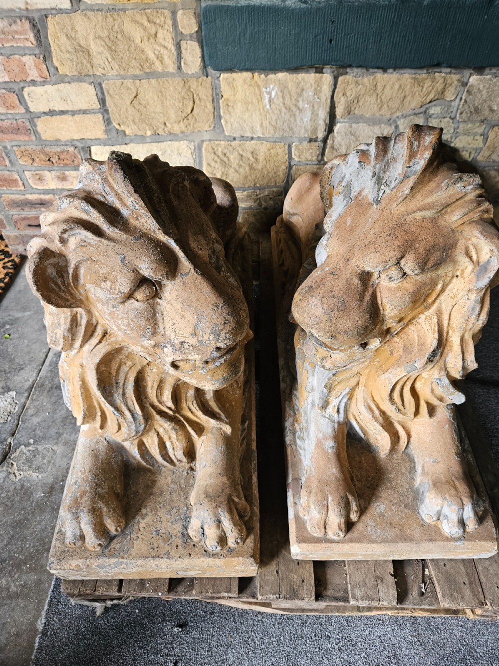 A pair of sculpted buff stone recumbent lion statues with detailed manes resting on integrated rectangular bases. View III