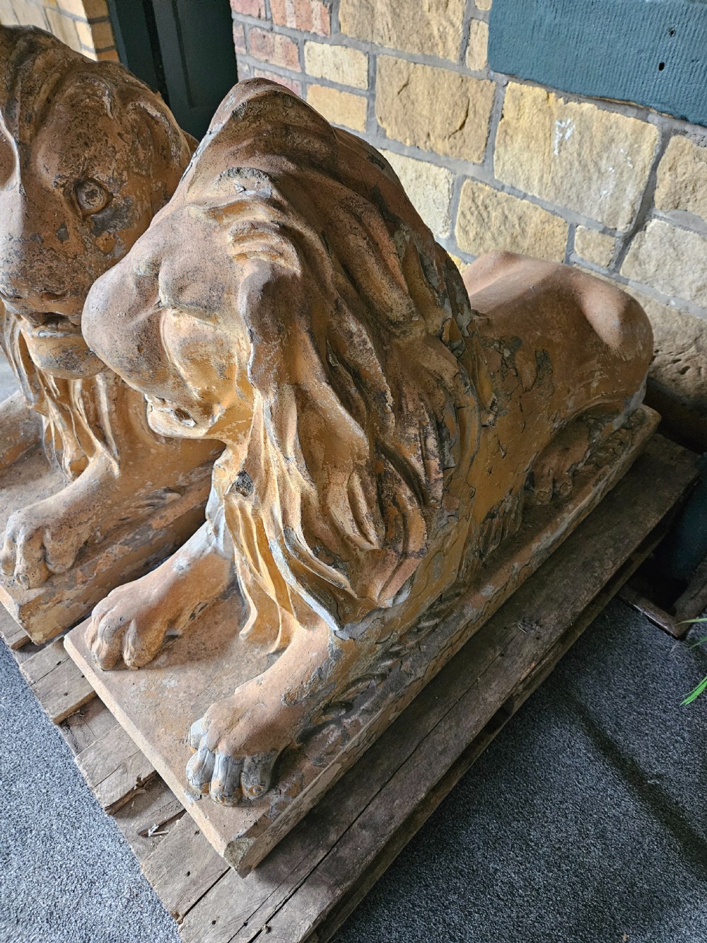 A pair of sculpted buff stone recumbent lion statues with detailed manes resting on integrated rectangular bases. View IV