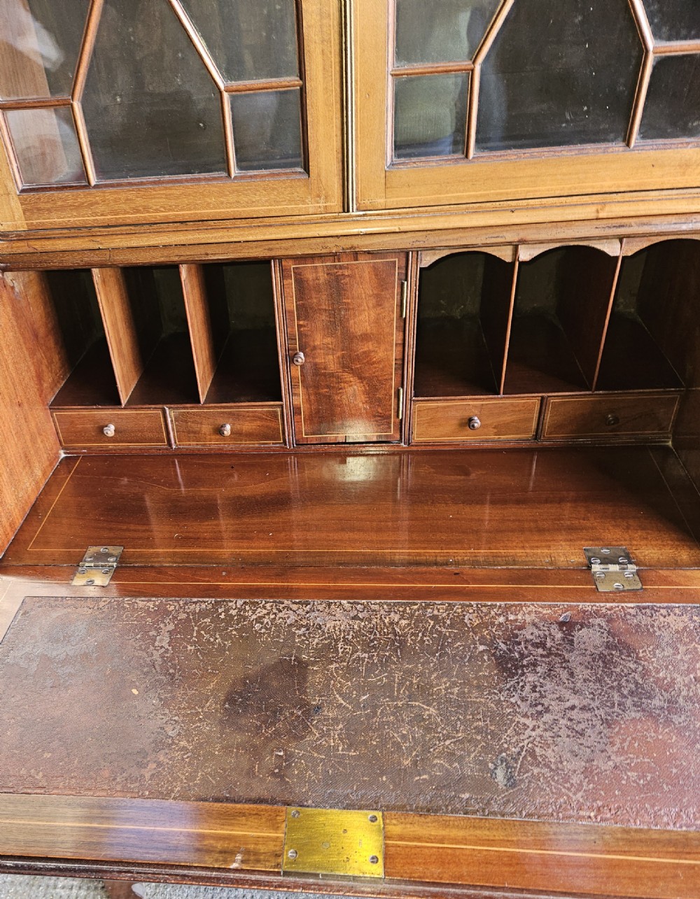 A mahogany bureau bookcase featuring a pediment top, geometric astragal glazed glass doors, a slant-front writing flap with oval inlay, and three drawers below. View IV