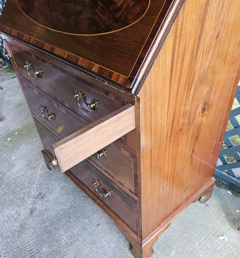 A mahogany bureau bookcase featuring a pediment top, geometric astragal glazed glass doors, a slant-front writing flap with oval inlay, and three drawers below. View VI