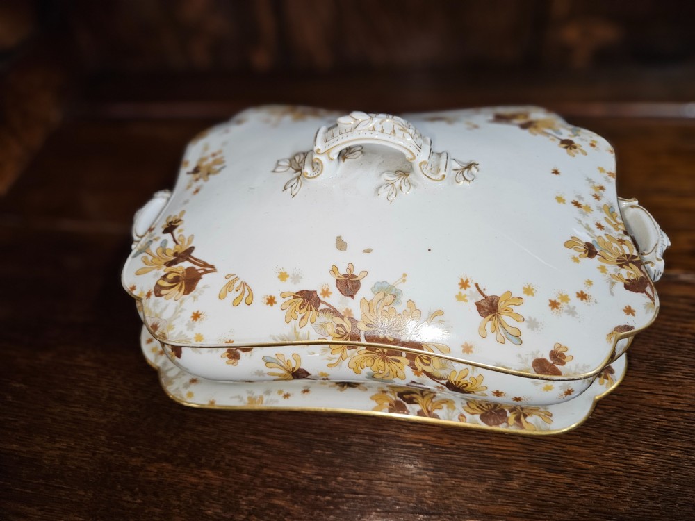 A white French porcelain dinner service with gold floral motifs displayed on an oak dresser and table. View III
