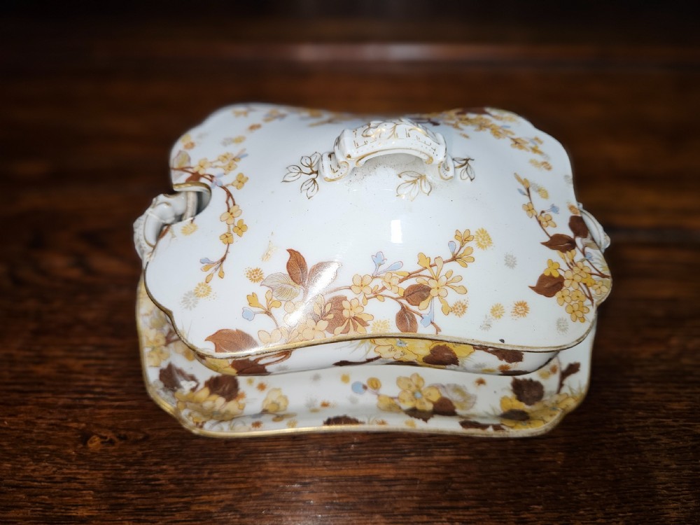 A white French porcelain dinner service with gold floral motifs displayed on an oak dresser and table. View IV