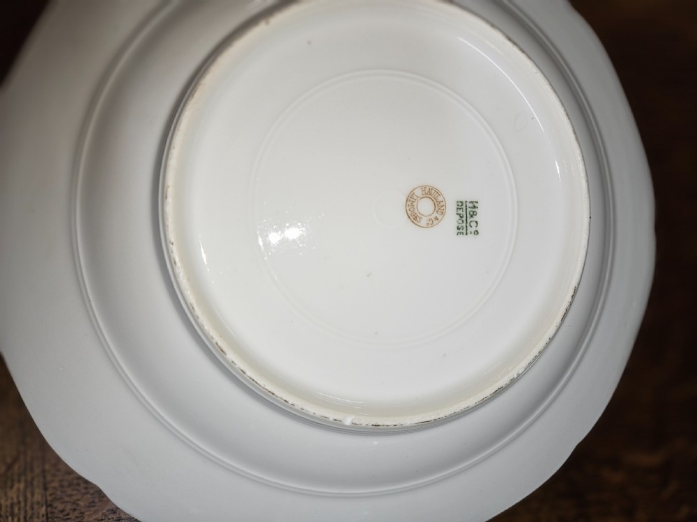 A white French porcelain dinner service with gold floral motifs displayed on an oak dresser and table. View V