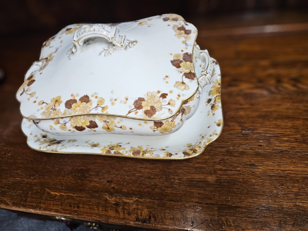A white French porcelain dinner service with gold floral motifs displayed on an oak dresser and table. View VI