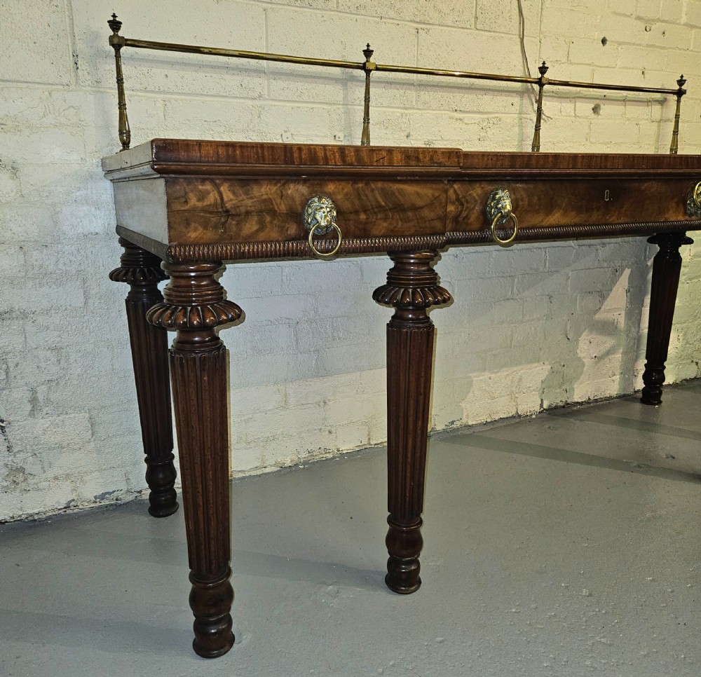 A Regency mahogany serving table featuring a brass gallery rail, lion mask ring handles, and six reeded tapered legs. View III