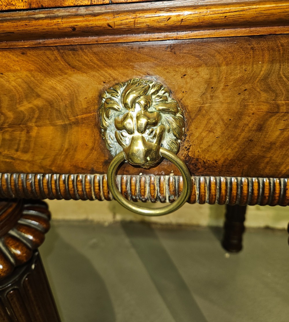 A Regency mahogany serving table featuring a brass gallery rail, lion mask ring handles, and six reeded tapered legs. View V