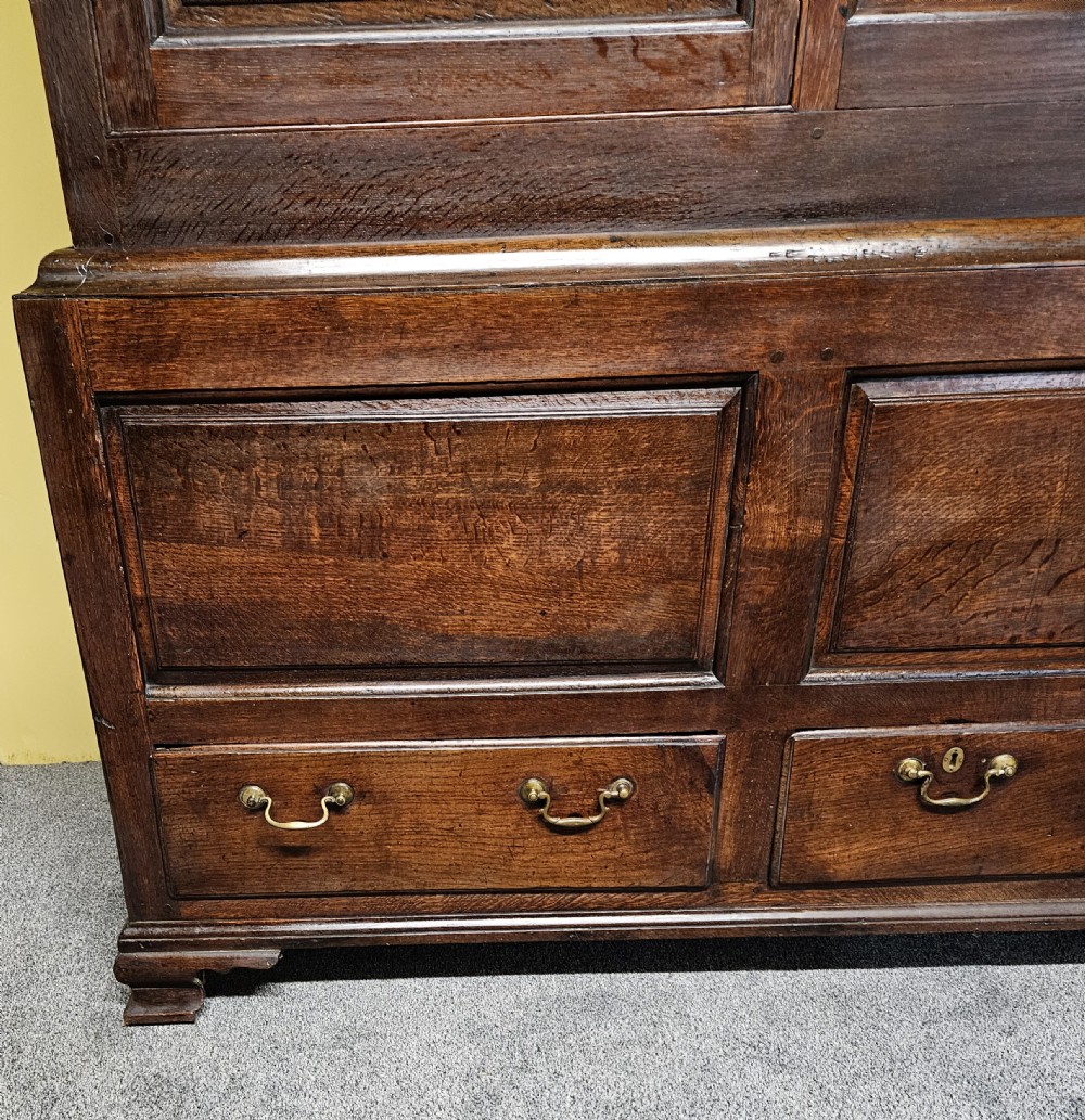 A large period dark oak livery cupboard featuring fielded arch-topped panel doors above a lower section fitted with drawers and brass hardware. View XVII