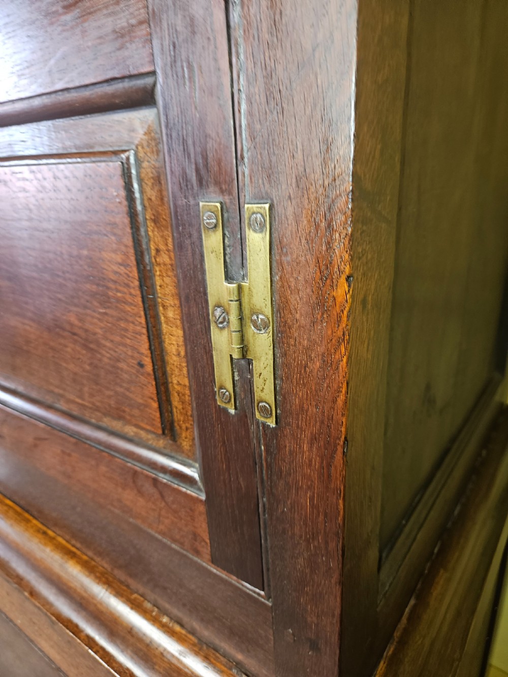 A large period dark oak livery cupboard featuring fielded arch-topped panel doors above a lower section fitted with drawers and brass hardware. View XVIII