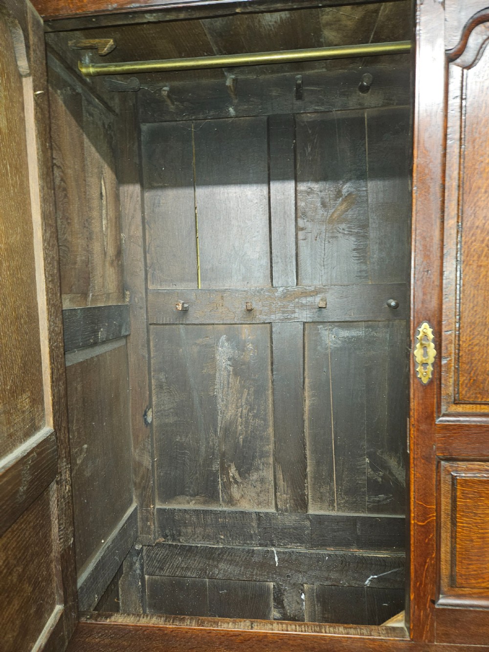 A large period dark oak livery cupboard featuring fielded arch-topped panel doors above a lower section fitted with drawers and brass hardware. View XX