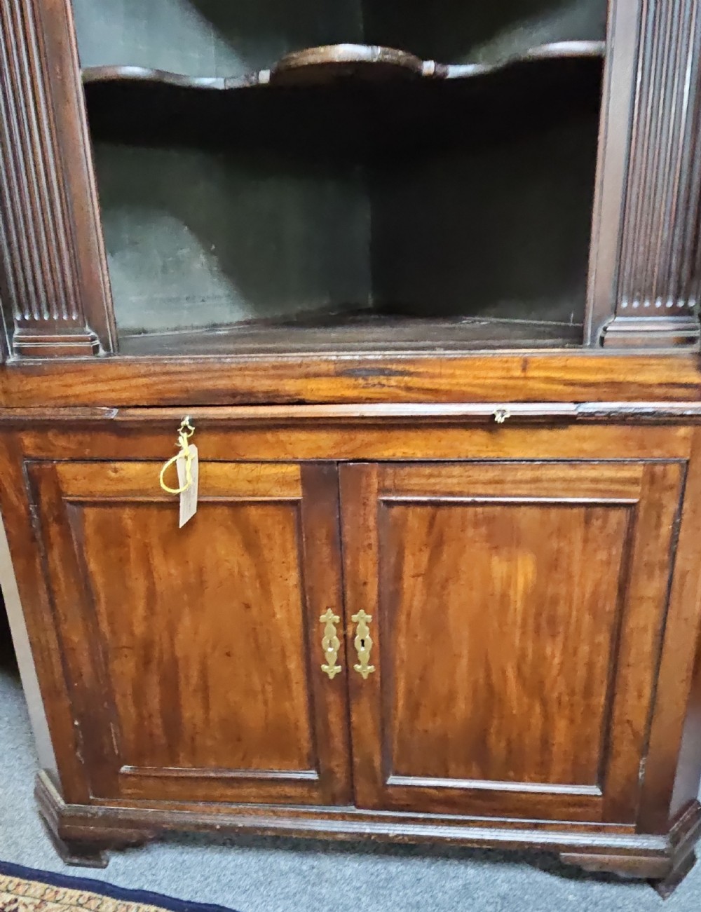 A tall two-tier Georgian mahogany corner cabinet with open upper panelled doors revealing arched interior shelving, set above a two-door base cabinet. View II