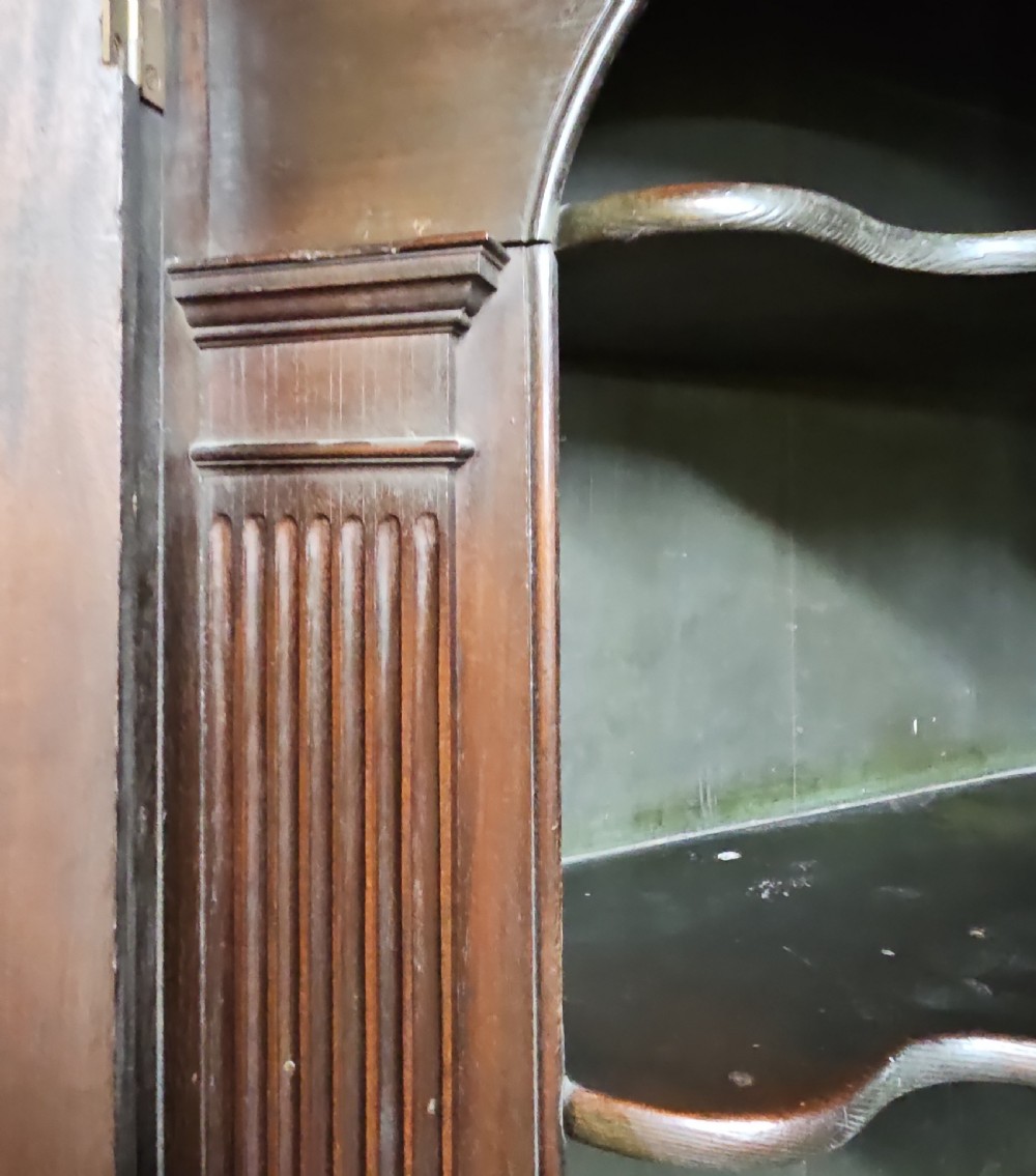 A tall two-tier Georgian mahogany corner cabinet with open upper panelled doors revealing arched interior shelving, set above a two-door base cabinet. View III