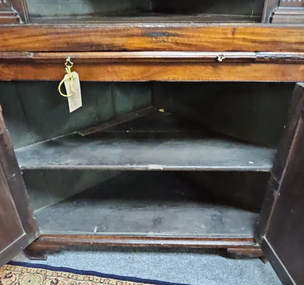 A tall two-tier Georgian mahogany corner cabinet with open upper panelled doors revealing arched interior shelving, set above a two-door base cabinet. View V