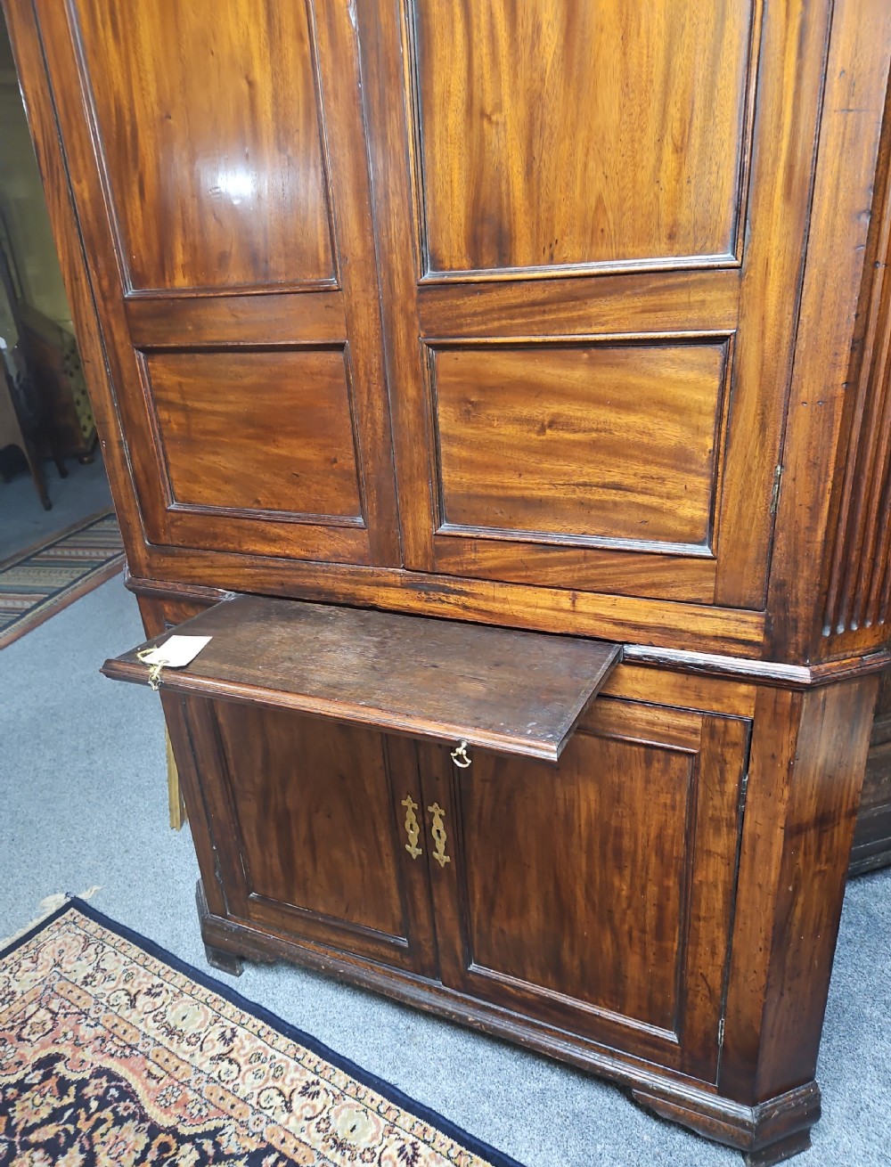 A tall two-tier Georgian mahogany corner cabinet with open upper panelled doors revealing arched interior shelving, set above a two-door base cabinet. View XIX