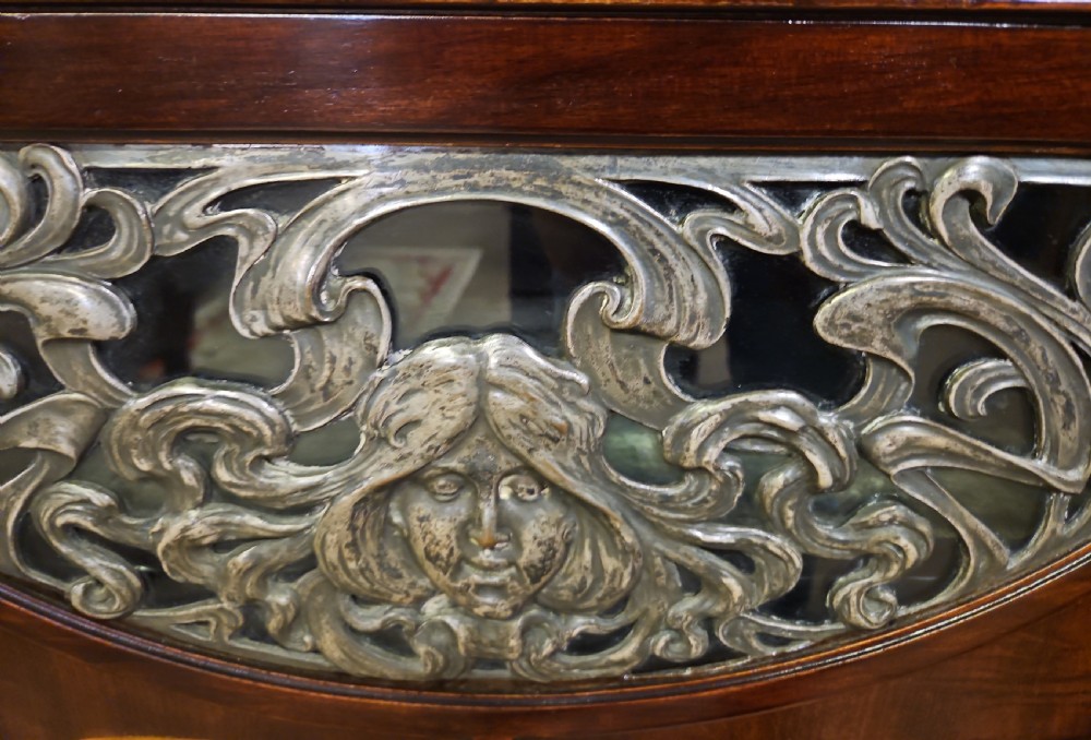 An Art Nouveau dark mahogany music cabinet featuring detailed wood marquetry, a pierced metal cartouche panel, and an upper mirrored gallery shelf. View XI
