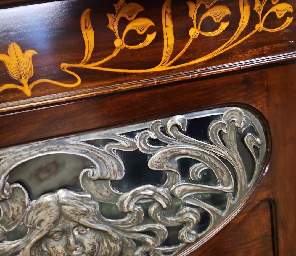 An Art Nouveau dark mahogany music cabinet featuring detailed wood marquetry, a pierced metal cartouche panel, and an upper mirrored gallery shelf. View XII
