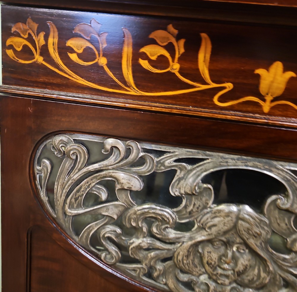 An Art Nouveau dark mahogany music cabinet featuring detailed wood marquetry, a pierced metal cartouche panel, and an upper mirrored gallery shelf. View XIII
