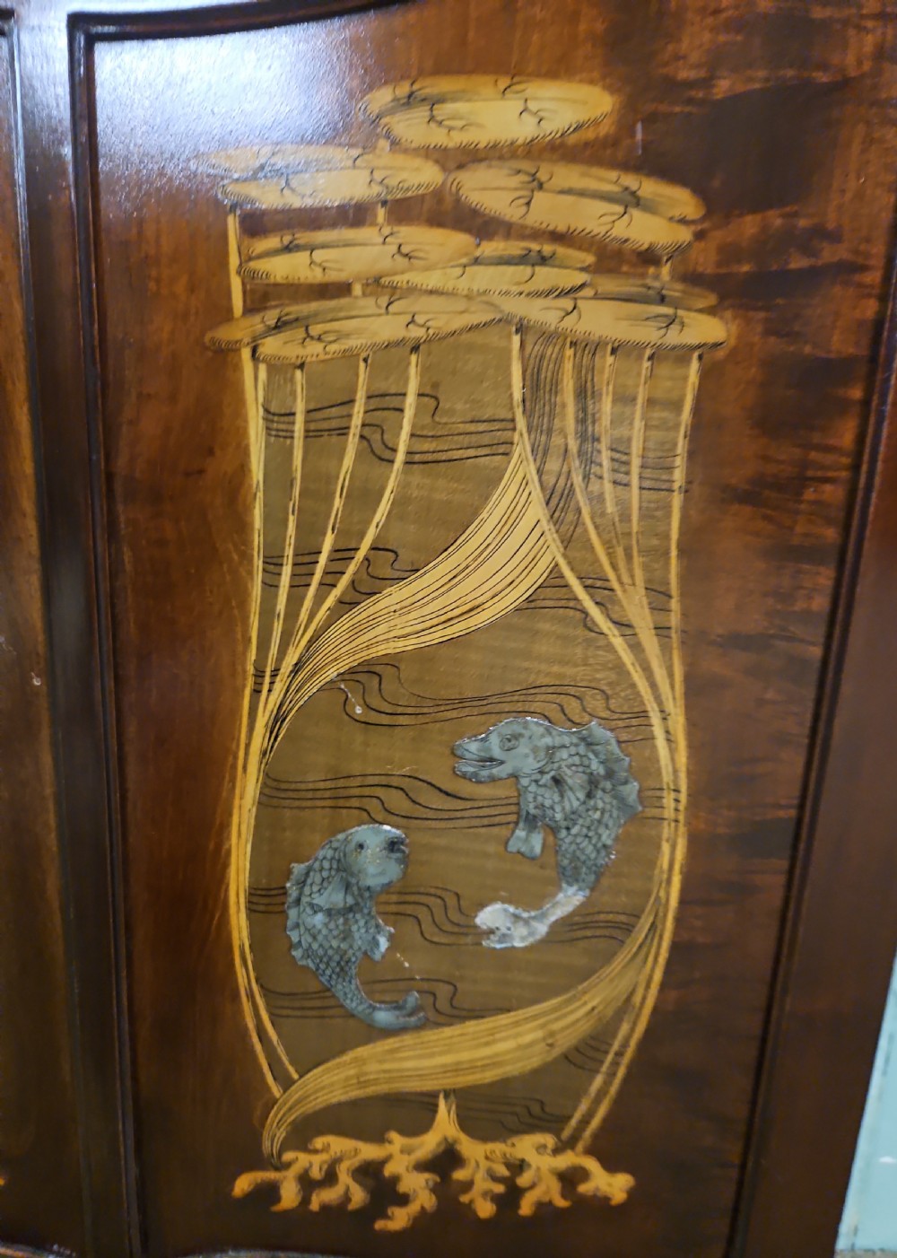 An Art Nouveau dark mahogany music cabinet featuring detailed wood marquetry, a pierced metal cartouche panel, and an upper mirrored gallery shelf. View XV