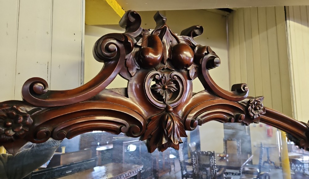 A Victorian mahogany sideboard with a large carved scrollwork framed mirror top, a serpentine surface, and twin pedestal cupboards with oval mouldings. View VII