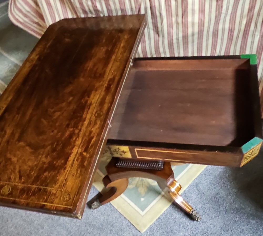 A Regency rosewood games table featuring brass inlay embellishments, a central pedestal, and splayed quadripartite legs with brass caps. View VIII